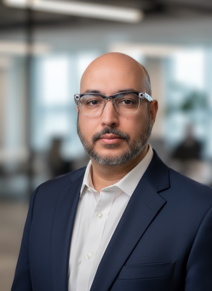 Fernando in a navy blazer and clear-framed glasses